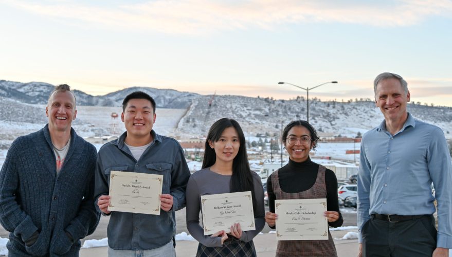 five people posing in front of snowy mountains