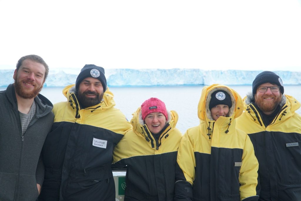 Five people in front of ocean and ice